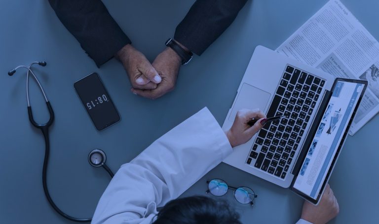 patient meeting with doctor at desk with laptop and stethoscope